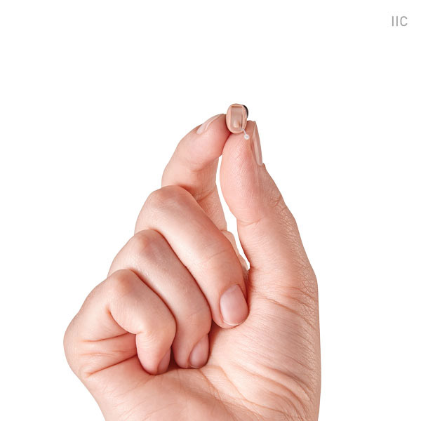 Doctor Holding a Small Hearing Aid Between Fingers in Castle Rock, CO