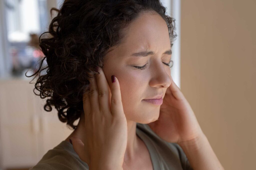 Female holding her ears and experiencing pain in the ear